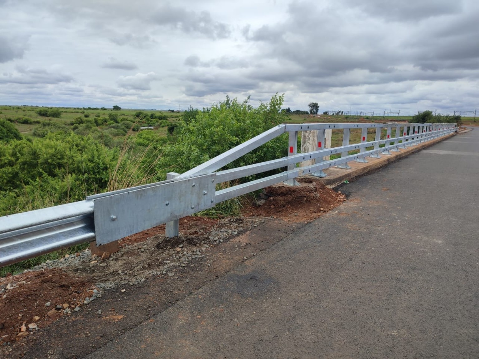 Galvanized bridge parapet and guardrail beside a rural road