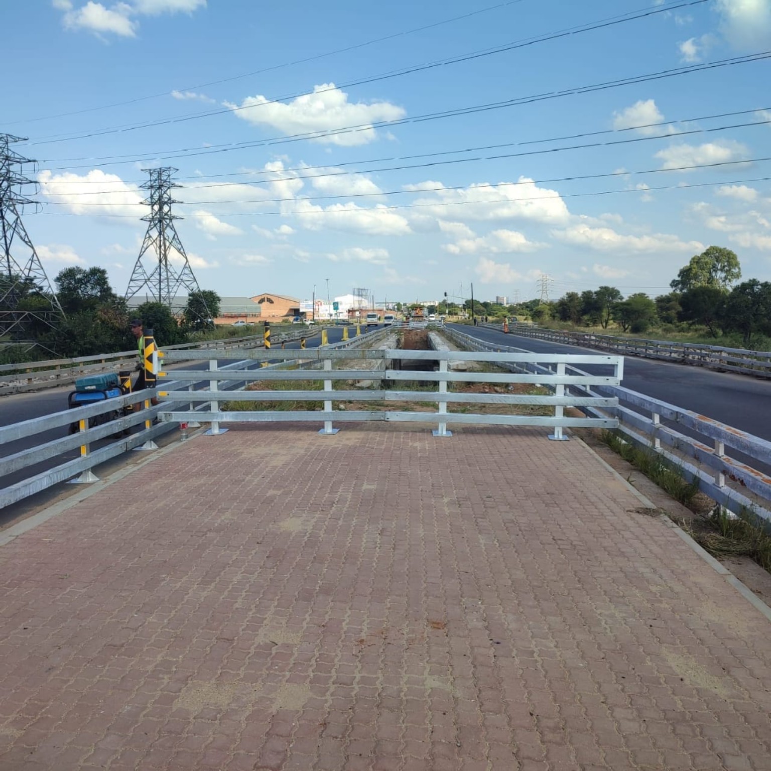 Galvanized safety railings separating a paved work zone from the road